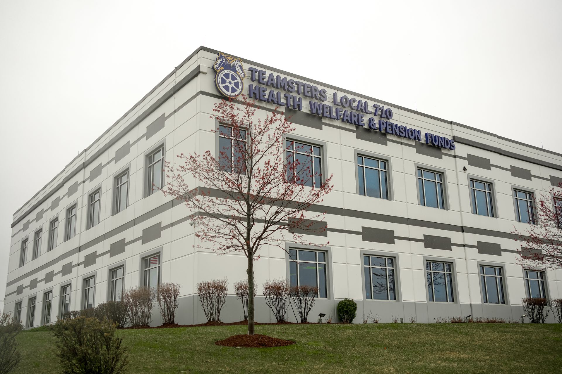 Exterior of a white two-story office building with blue windows and a sign on the roof