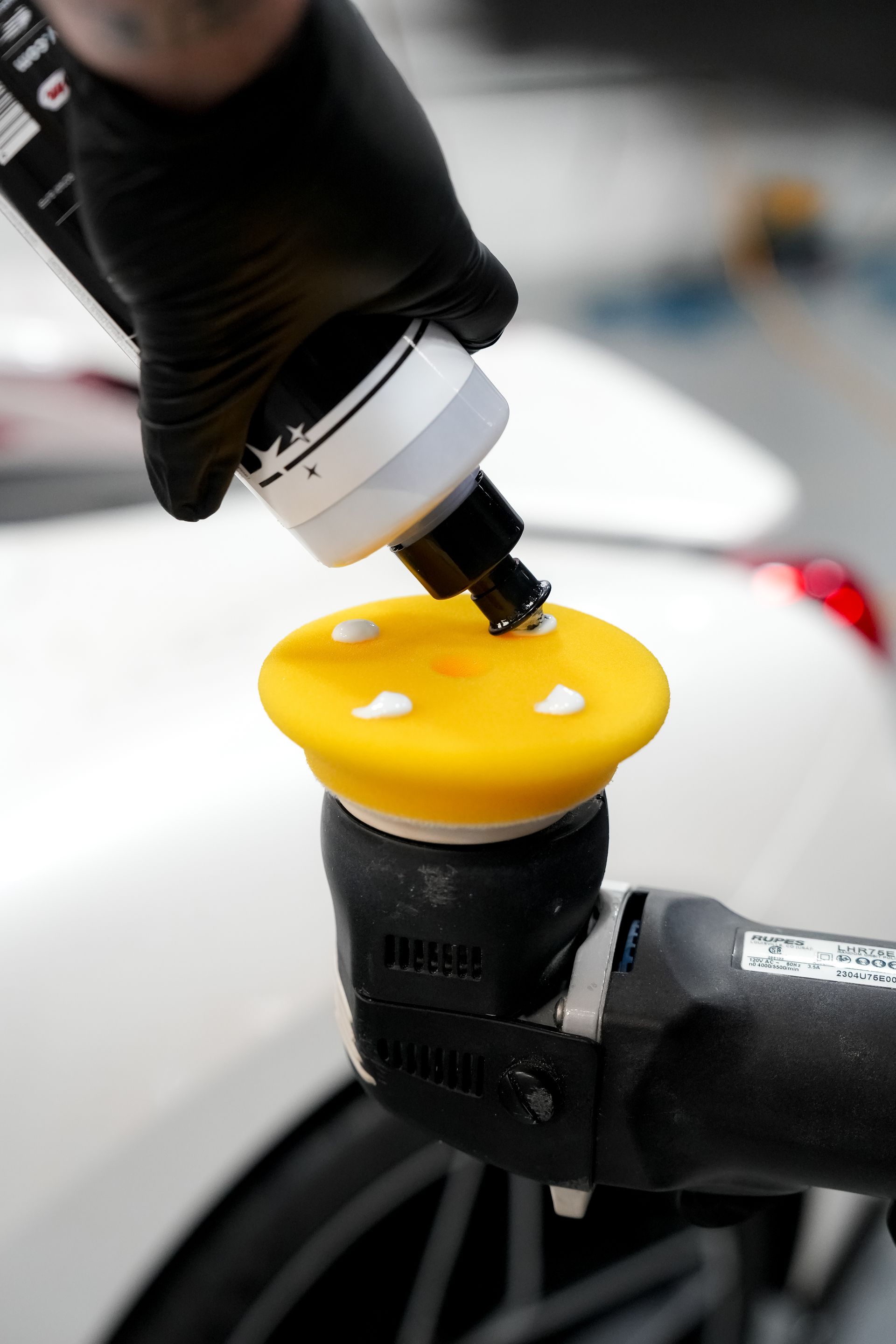 Gloved hand adding fluid to a yellow motorcycle brake fluid reservoir