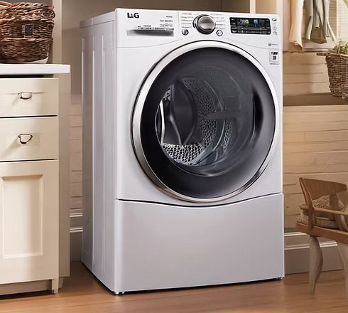A white LG front-load washing machine sits in a laundry room next to a cabinet with wicker baskets.
