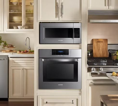 Stainless steel microwave and oven built into cream-colored kitchen cabinetry.