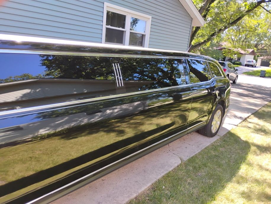 Black limousine parked beside a house on a sunny residential street