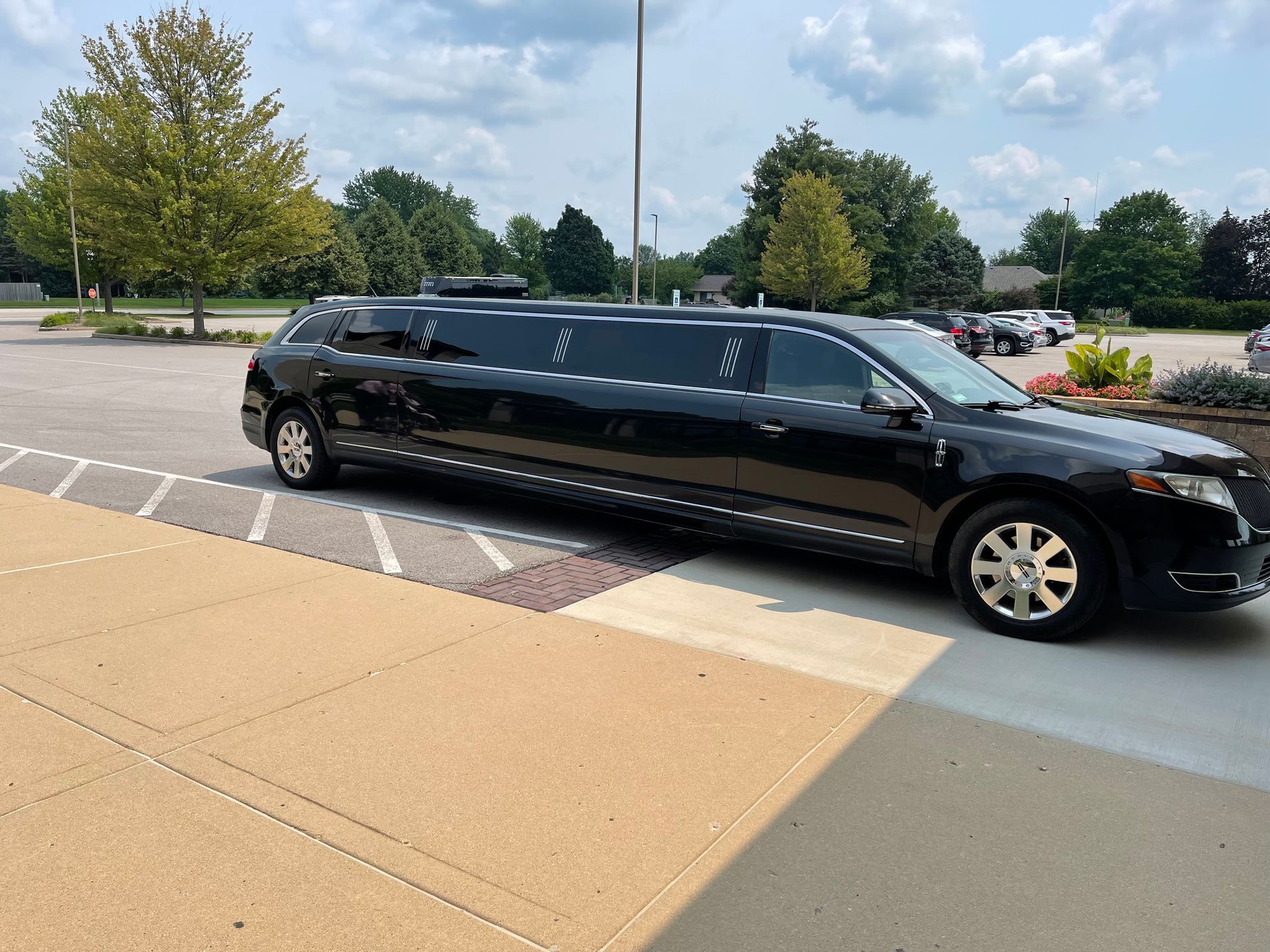 Black stretch limousine parked outside on a concrete lot under a cloudy sky
