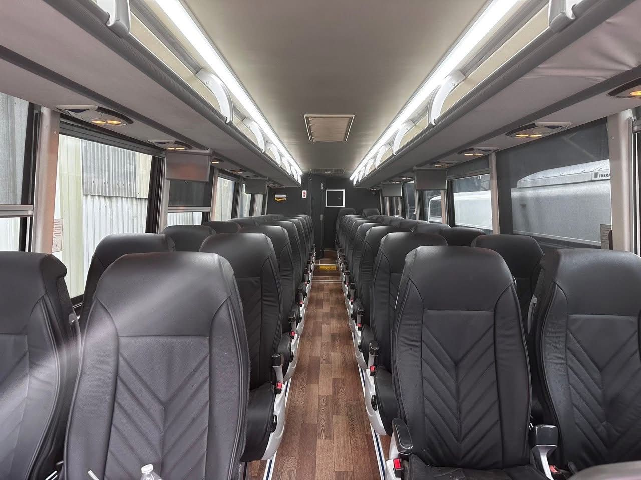 Empty bus interior with black seats and wood-patterned aisle flooring