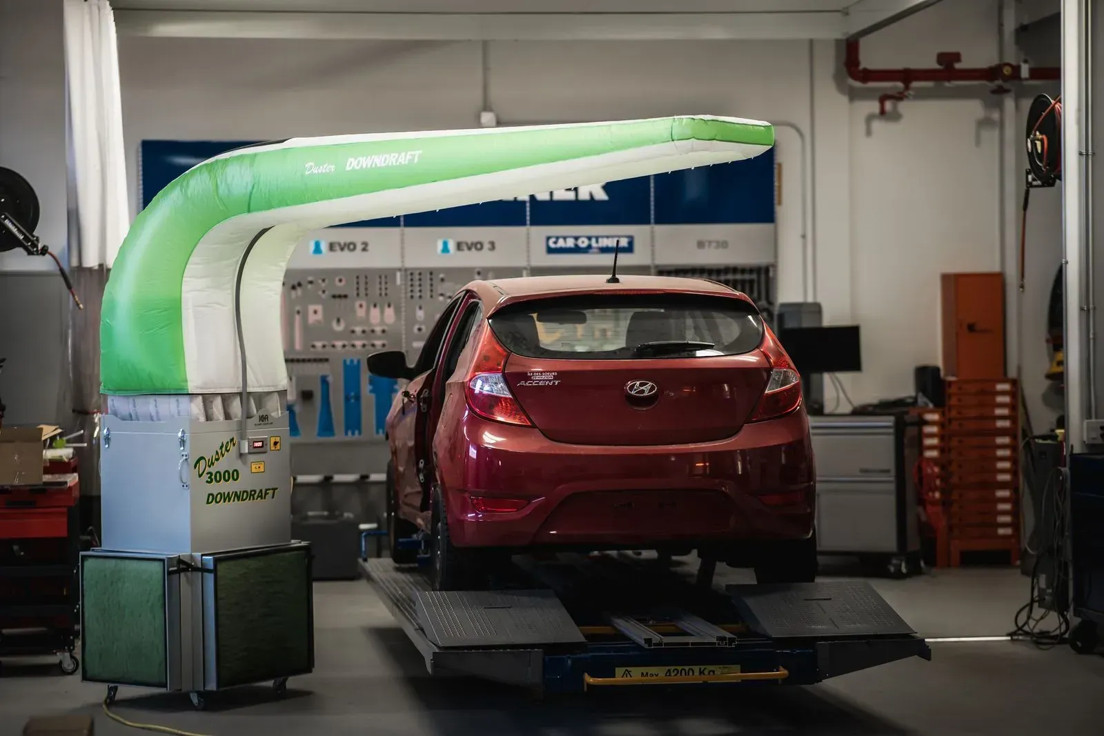 Une voiture rouge est assise sur un ascenseur dans un garage.