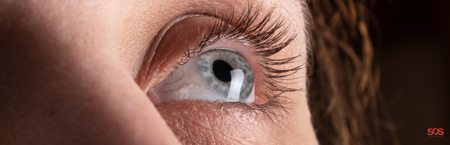 Close-up de um olho azul olhando para cima, com cílios longos e definidos.