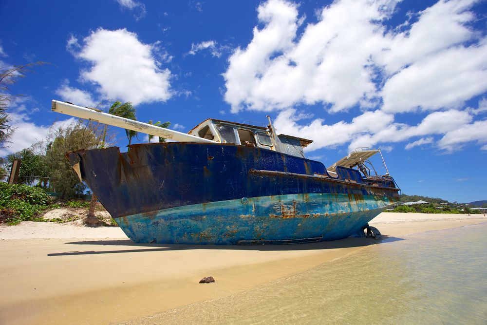 A Blue Boat is Sitting on a Sandy Beach — On Demand Diggers & Demolitions in Sunshine Coast, QLD