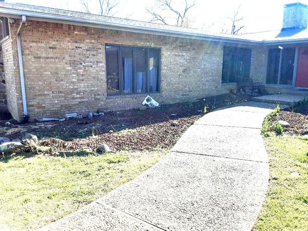 A brick house with a concrete walkway leading to it.