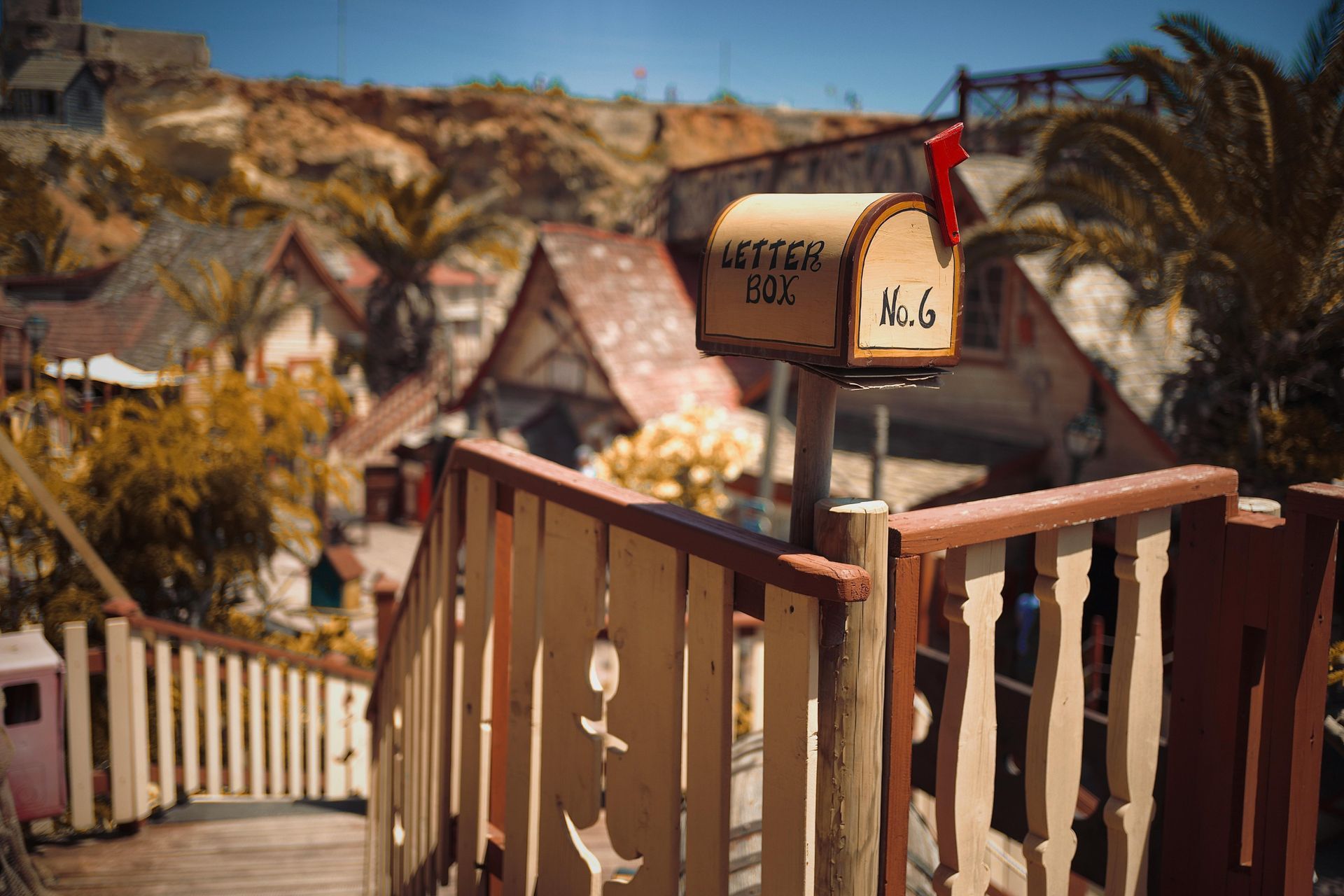 A wooden mailbox is sitting on top of a wooden railing.