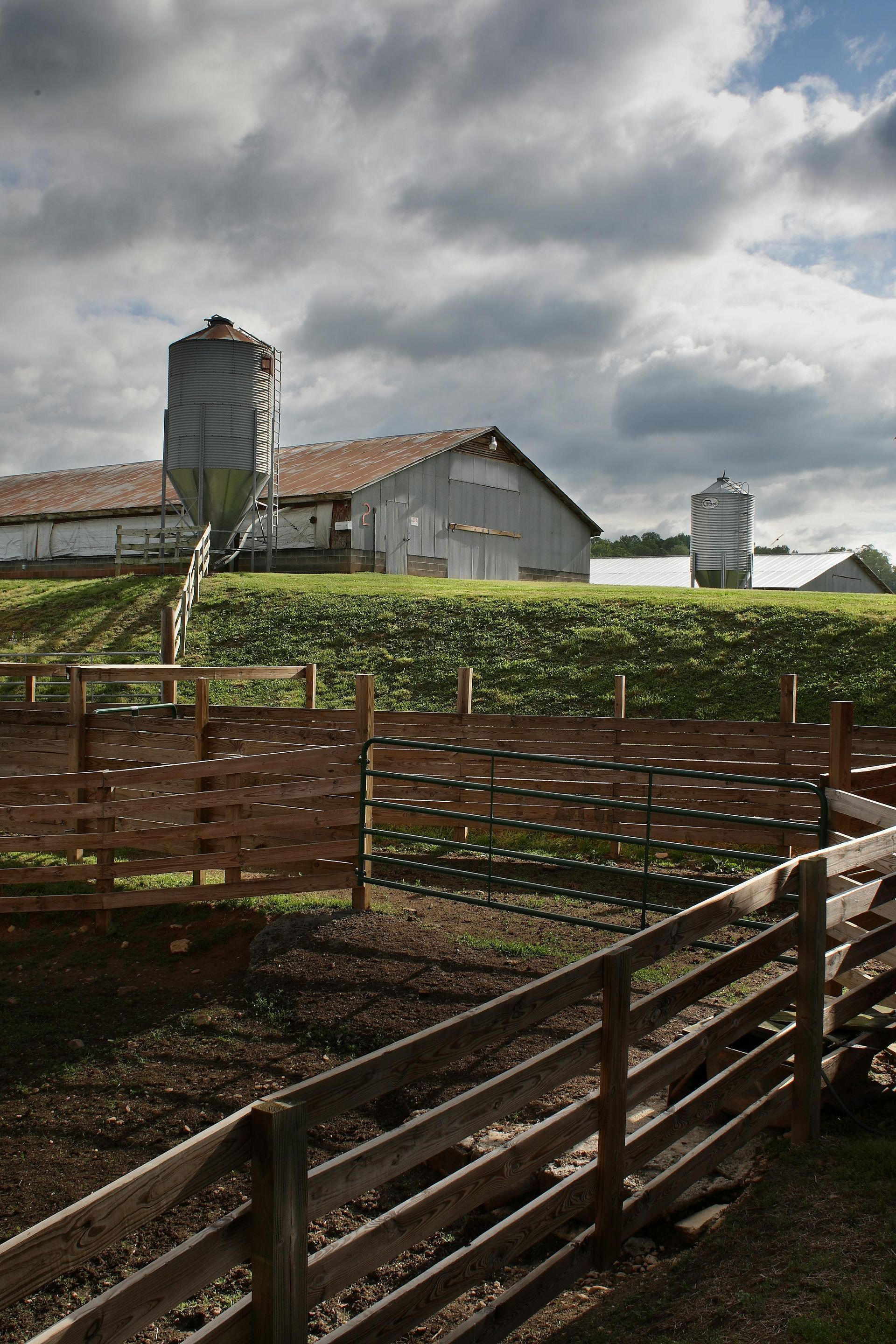 A farm with a wooden fence and a silo in the background