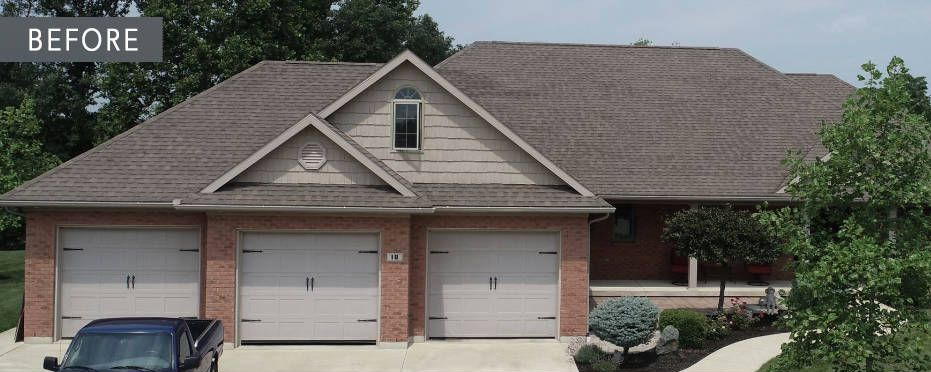 House exterior with three-car garage, red brick, and brown roof. A blue truck is parked in front of the garage.