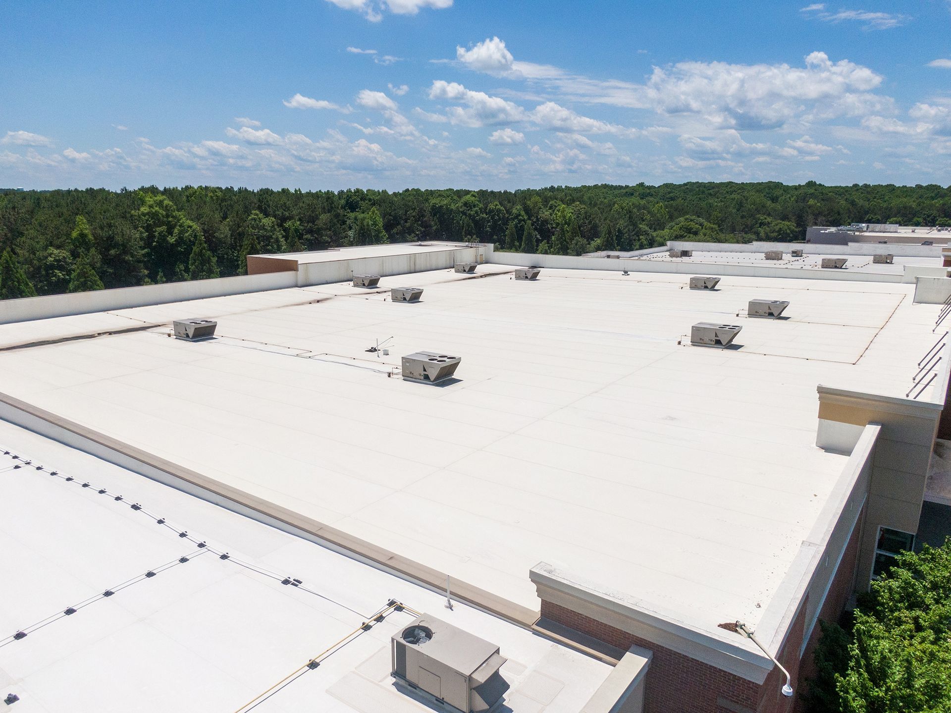 White commercial flat roof with HVAC units under a blue sky.