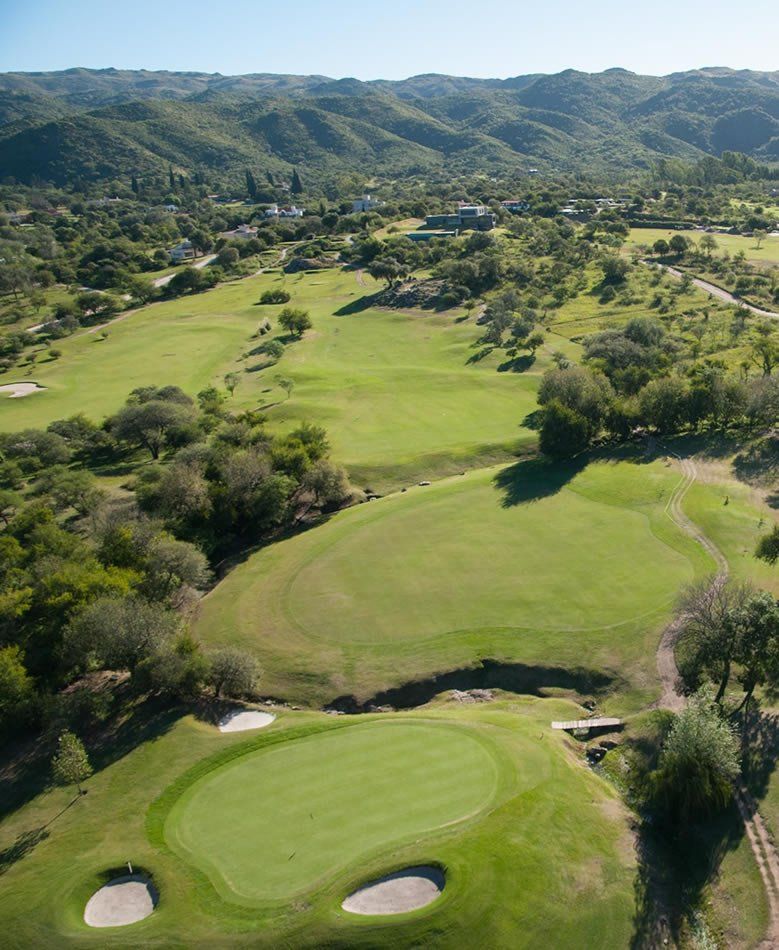 Una vista aérea de un campo de golf con montañas al fondo.