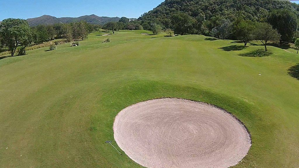 Vista aérea de un campo de golf con un bunker en medio.