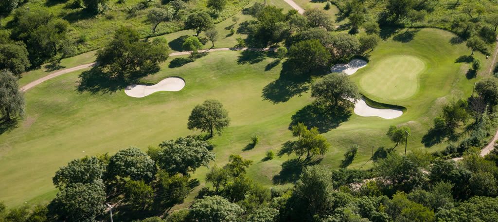 Una vista aérea de un campo de golf rodeado de árboles.