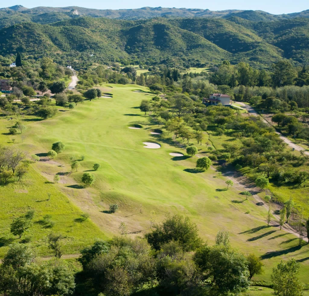 Una vista aérea de un campo de golf con montañas al fondo.