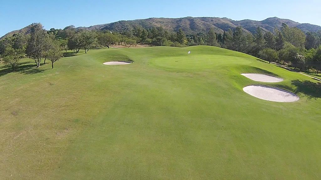 Una vista aérea de un campo de golf con montañas al fondo.