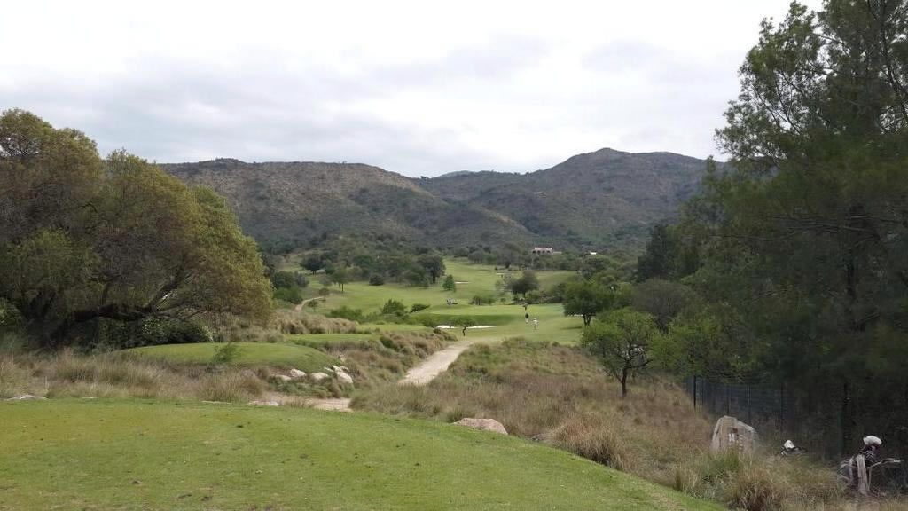 Una vista de un campo de golf con montañas al fondo.