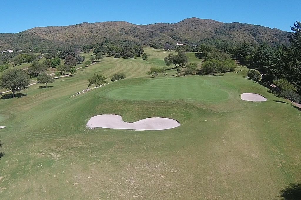 Una vista aérea de un campo de golf con montañas al fondo.