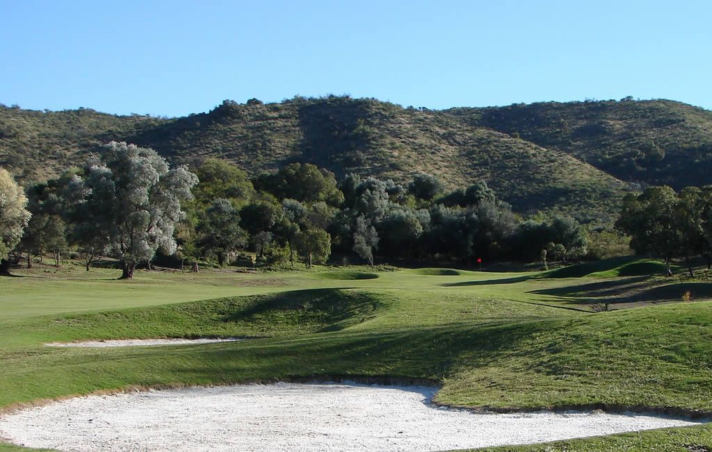 Un campo de golf verde y exuberante con montañas al fondo