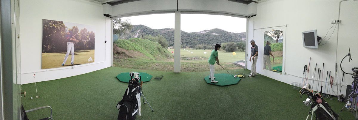 Una persona practica golf en un simulador de golf cubierto.