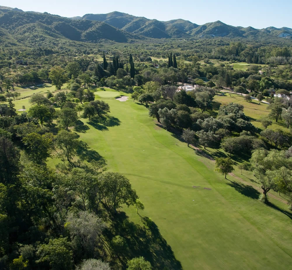 Una vista aérea de un campo de golf con montañas al fondo.