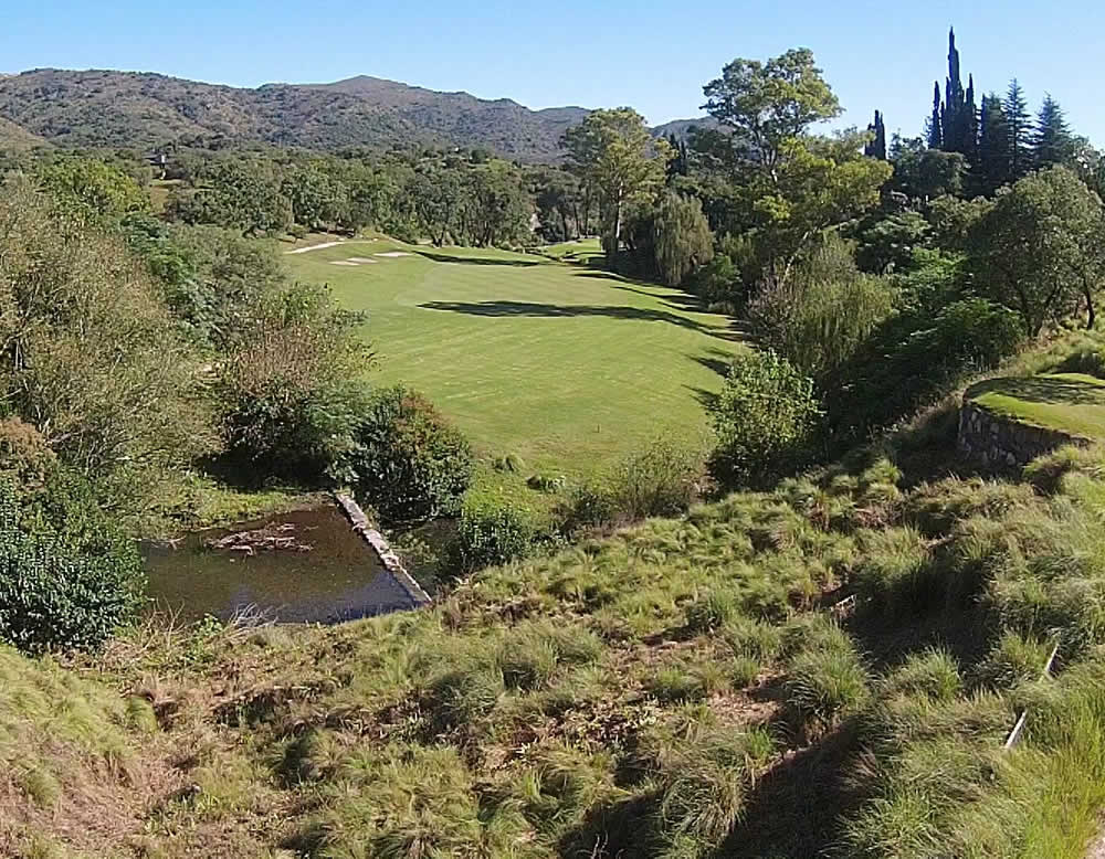 Una vista aérea de un campo de golf con un estanque en el medio.
