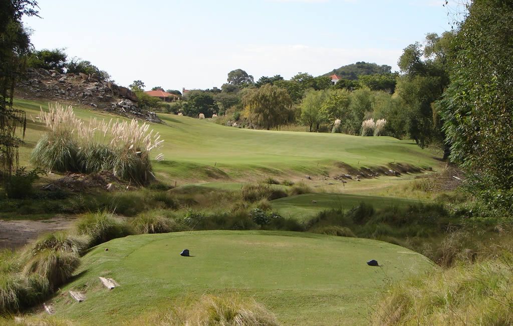 Un campo de golf con mucho césped y árboles.