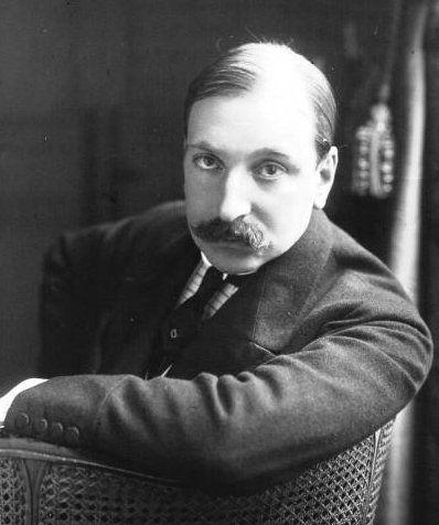 Una fotografía en blanco y negro de un hombre con bigote sentado en una silla.