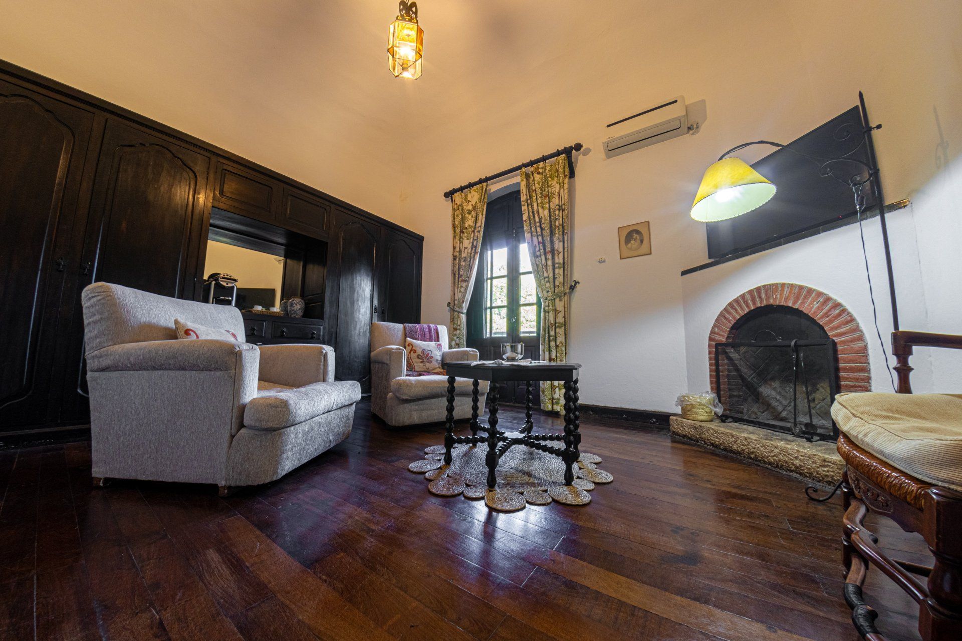 Un salón con sofá, silla, mesa y chimenea.