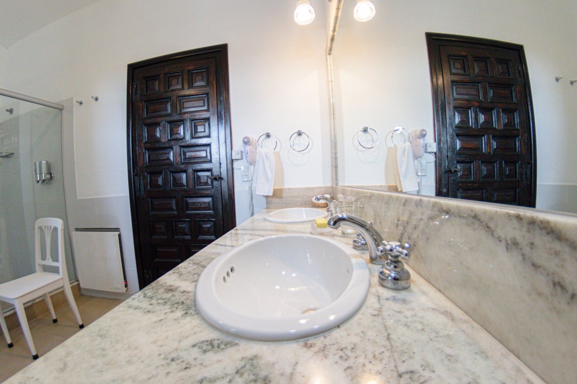 Un baño con lavabo, espejo y silla.