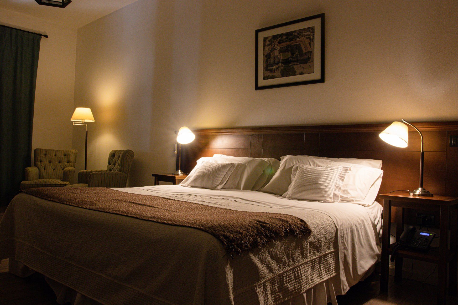 Una habitación de hotel con una cama king size y dos lámparas.
