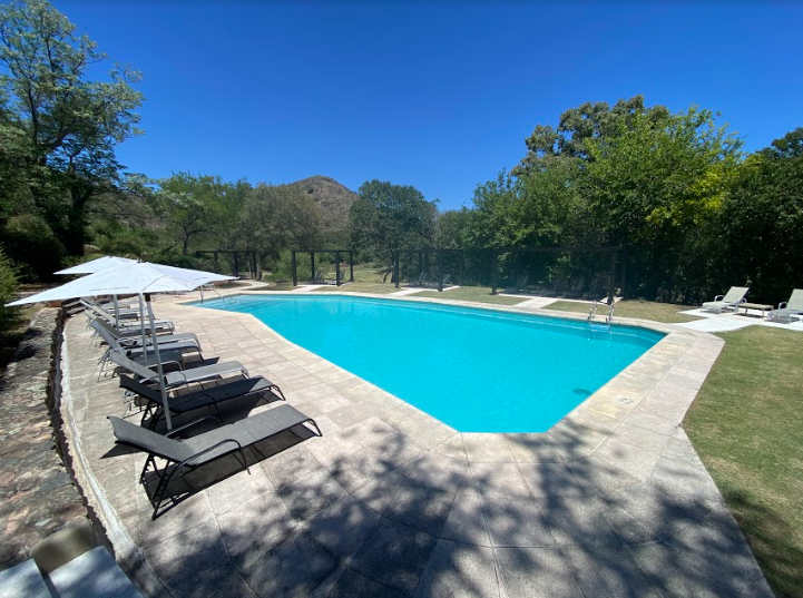 Una gran piscina rodeada de tumbonas y sombrillas en un día soleado.