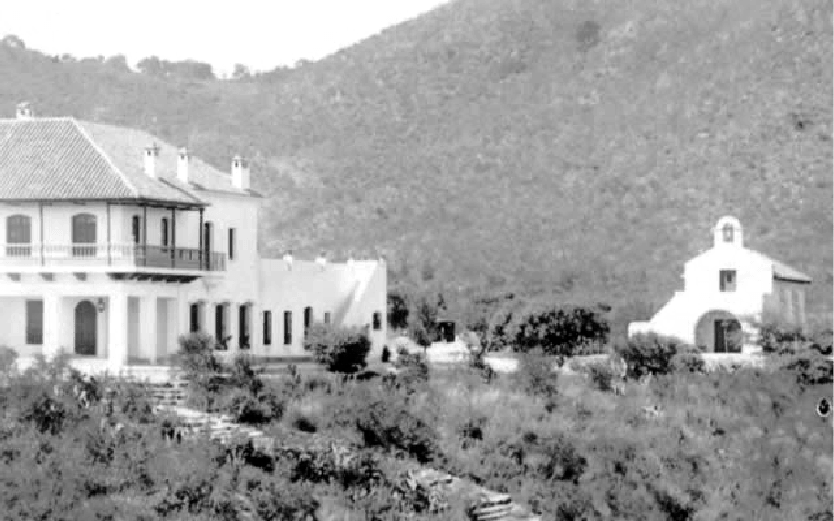 Una fotografía en blanco y negro de una casa y una pequeña iglesia.