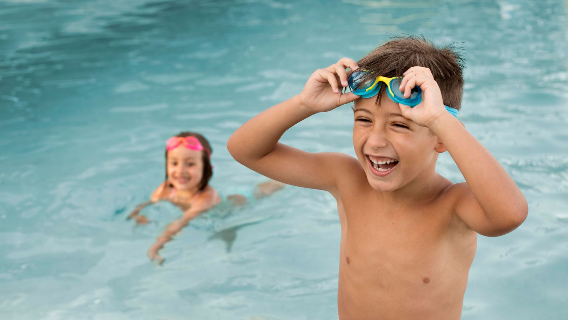 Un niño con gafas está parado en una piscina.
