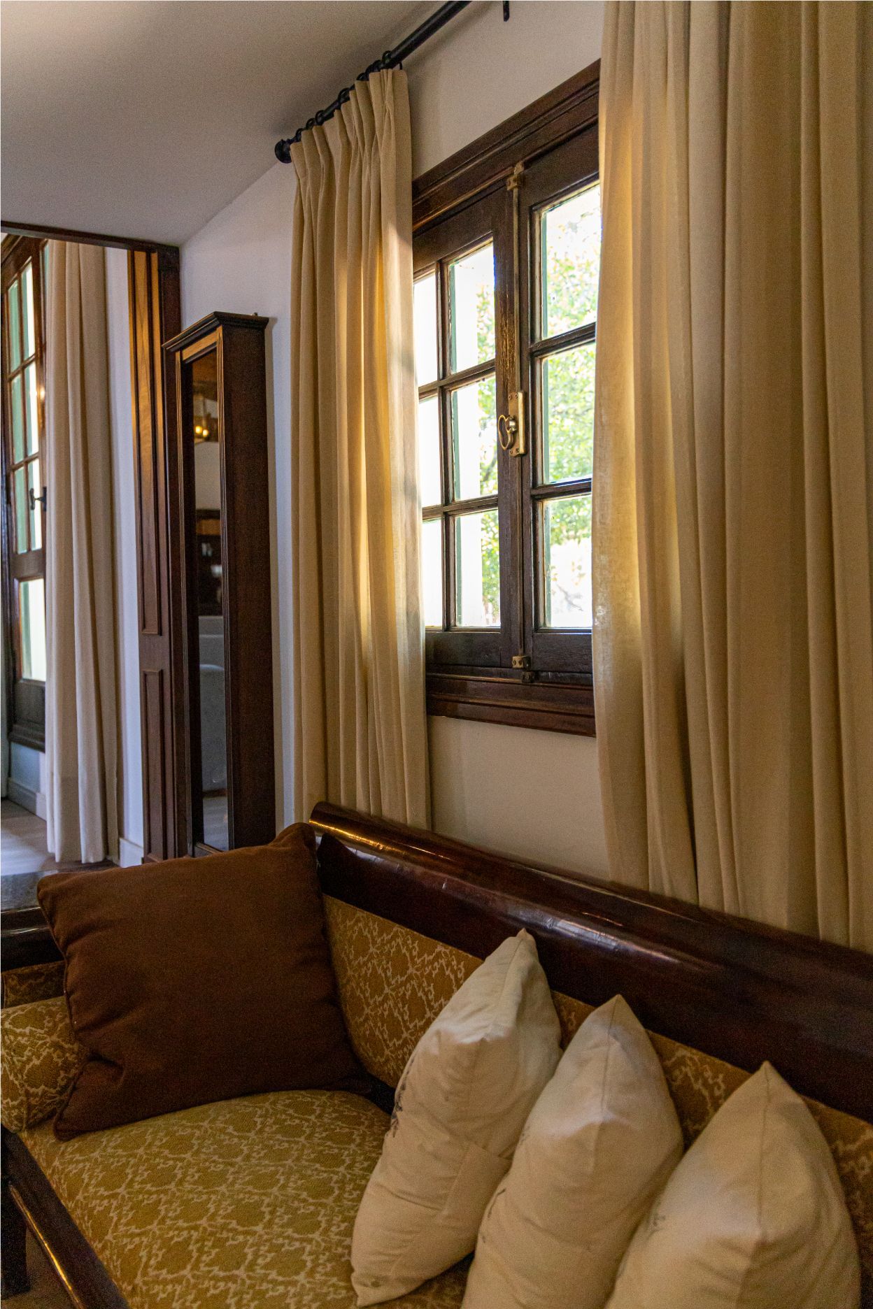 Un sofá con almohadas en una sala de estar junto a una ventana.