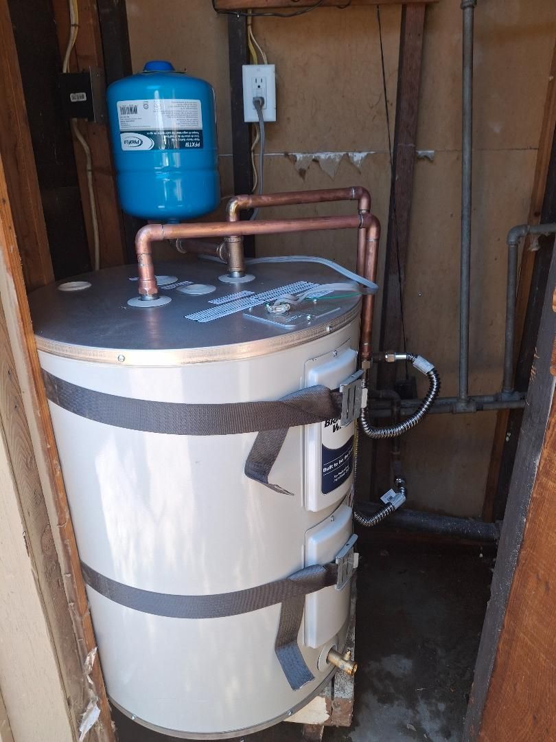 Water heater with blue expansion tank in a utility closet, with copper pipes and insulation.