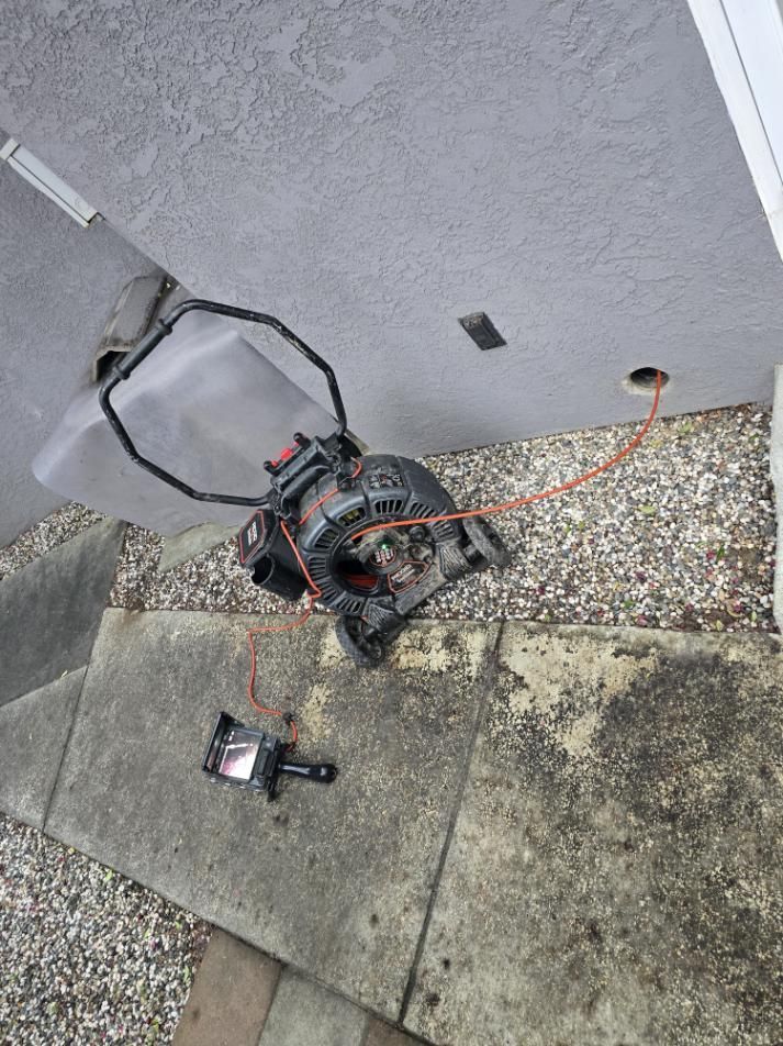 Tipped over small utility vehicle or mower on a gravel and concrete patio beside a wall