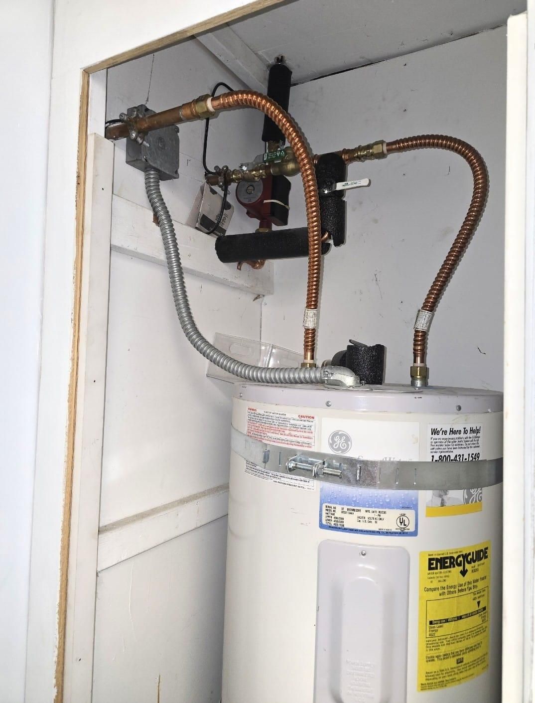 Gas water heater with exposed copper pipes in a small utility closet.