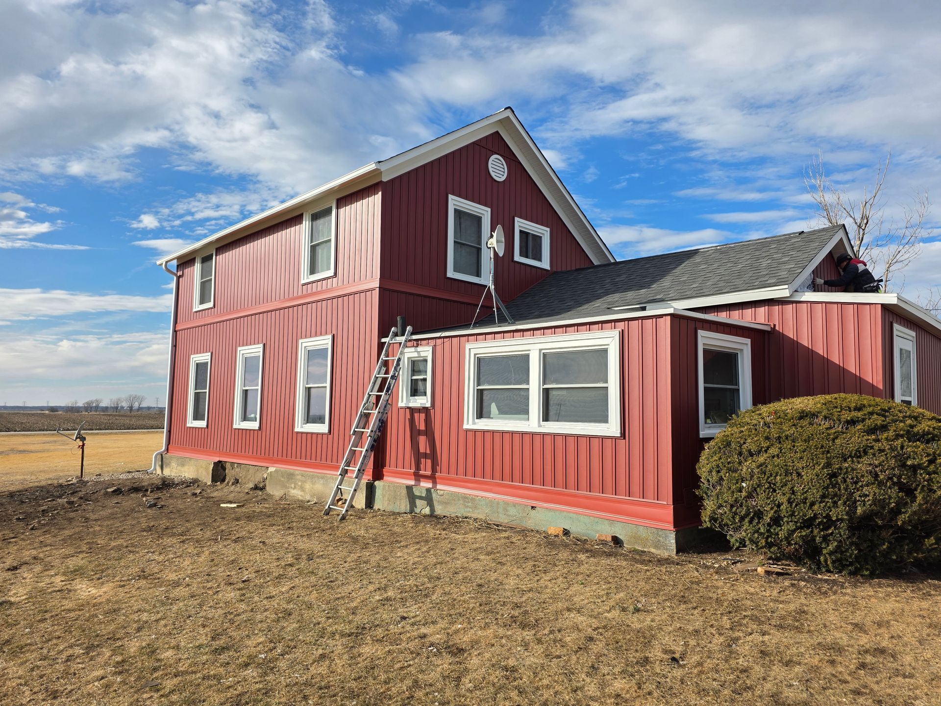 Hands nailing grey lap siding boards to a wooden frame.