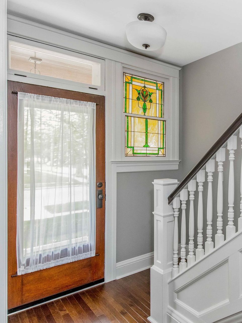 A wooden door with a stained glass window next to a staircase.