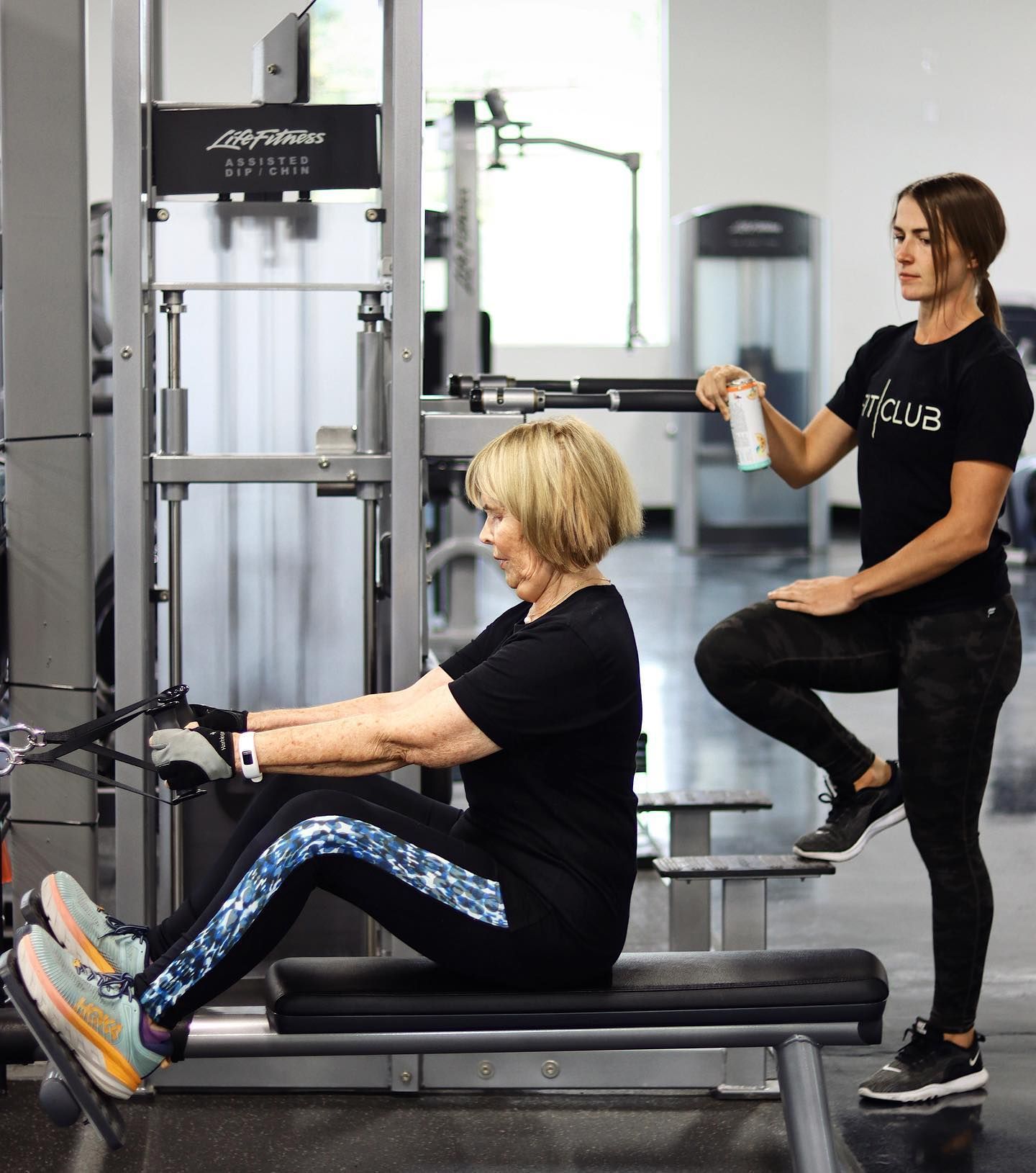 FitClub personal trainer guiding member on seated cable row for upper body strength.