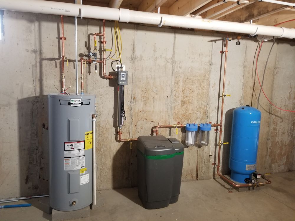 A basement with a water heater and a water tank.