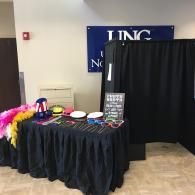 Event booth with black curtain backdrop and table of colorful accessories and props