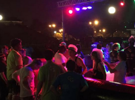 Crowd dancing under colorful lights at an outdoor nighttime event