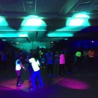 People dancing in a dark club with teal and purple lights