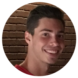 Smiling person in a red shirt in front of a brick wall, shown in a circular portrait