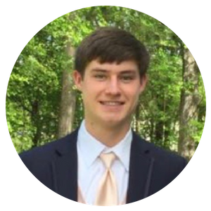 Portrait of a smiling young man in a suit and tie outdoors among trees