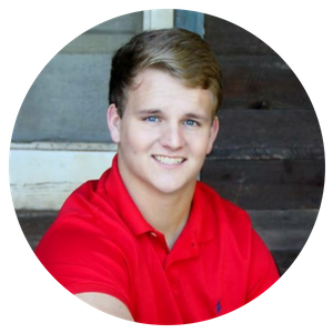 Smiling person in a red polo shirt against a rustic wooden wall