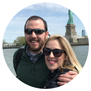 Smiling couple in sunglasses with the Statue of Liberty in the background