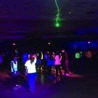 People dancing in a dark nightclub with purple and green lights